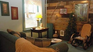 A cozy living room with a sofa, a wooden wall, a lamp, and a chair. - The Historic Union Hotel (Union)