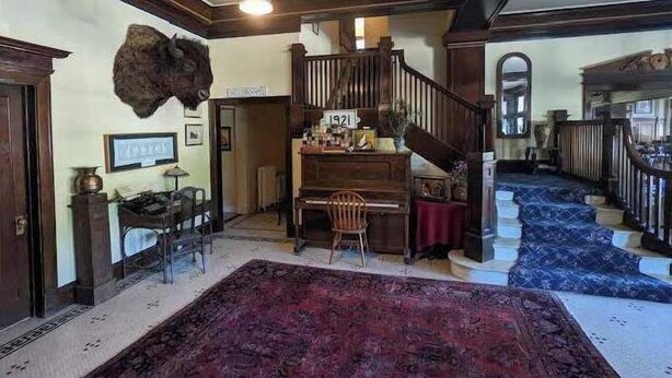 A grand foyer with a piano, a large rug, and a staircase. - The Historic Union Hotel (Union)