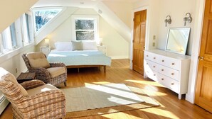 A bedroom with a sloped ceiling, a bed, a dresser, a chair, and a large window. - 4 Bedroom Beachside Surfer's Home (South Portland)