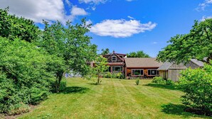 A large house with a well-maintained lawn and surrounding trees. - 4 Bedroom Beachside Surfer's Home (South Portland)