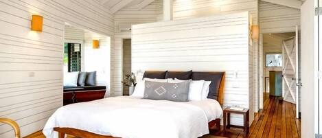 Um quarto com cama de madeira, uma mesinha de cabeceira, uma cadeira e um espelho na parede.