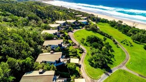 Luchtbeeld van een kustgebied met woonhuizen, een strand en een golfbaan.