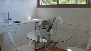 A compact kitchen with a sink, a washing machine, and a glass table with chairs. - 1 BR unit with leafy outlook & dedicated workspace (Glebe)