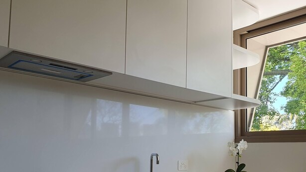 A modern kitchen with white cabinets, a stainless steel range, a built-in oven, a sink, and a window with a view of trees. - 1 BR unit with leafy outlook & dedicated workspace (Glebe)