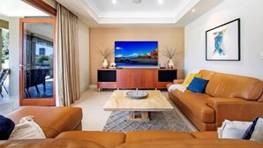 A modern living room with a sofa, coffee table, and TV. - Luxico Lakeland Keys (Heated Pool) (Broadbeach Waters)