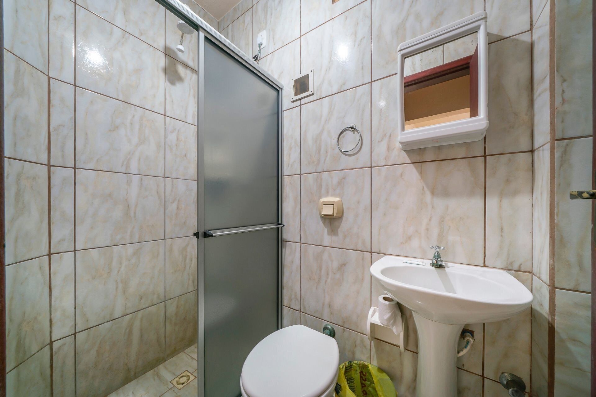 Een badkamer met douche, toilet en wastafel.