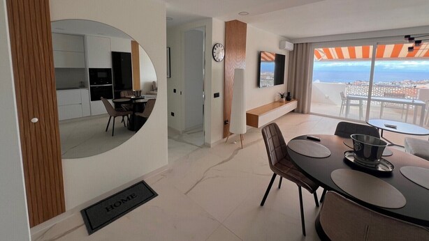 A modern apartment with a kitchen, dining area, and balcony with a city view. - Casa Margarita, Costa Adeje (Costa Adeje)