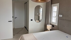 A modern hotel room with a large bed, a bedside lamp, a mirror, and a view of the outside through a window. - Casa Margarita, Costa Adeje (Costa Adeje)