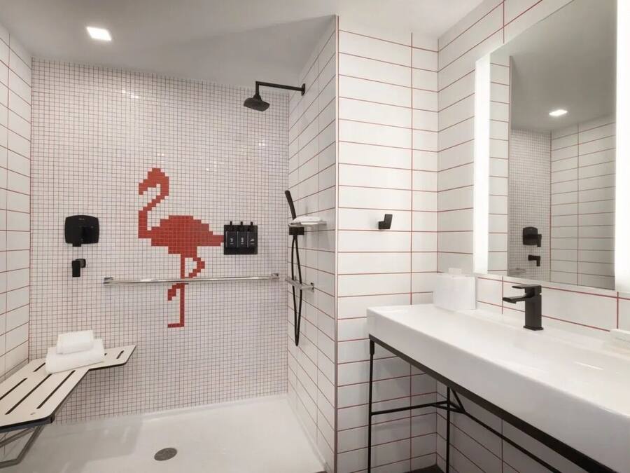 A modern bathroom with a shower, toilet, and sink, featuring a grid-patterned tile design and a mirror above the sink.
