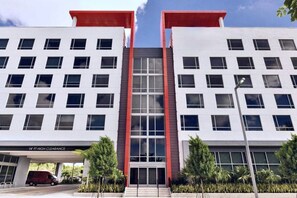 A modern building with a 14' high clearance entrance, multiple windows, and a red accent on the roof. - Kompose Boutique Hotel Miami Airport  (Miami)