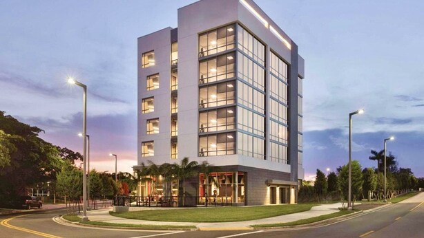 A modern multi-story hotel with a prominent glass facade, multiple balconies, and a well-lit entrance area. - Kompose Boutique Hotel Miami Airport  (Miami)
