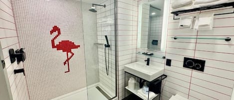 Een moderne badkamer met een glazen douchecabine, een witte wastafel en een spiegel erboven.