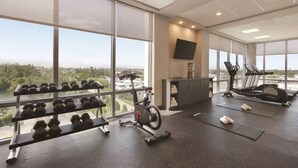 A gym with exercise equipment, large windows, and a view of the city. - Kompose Boutique Hotel Miami Airport  (Miami)
