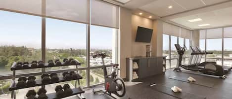 A gym with exercise equipment, large windows, and a view of the city.