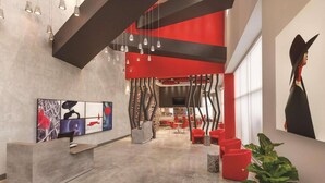 A modern interior with a reception desk, red seating, and abstract art. - Kompose Boutique Hotel Miami Airport  (Miami)