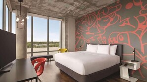 A modern hotel room with a large bed, a desk, and a chair. There is a large window providing a view of the outdoors. - Kompose Boutique Hotel Miami Airport  (Miami)