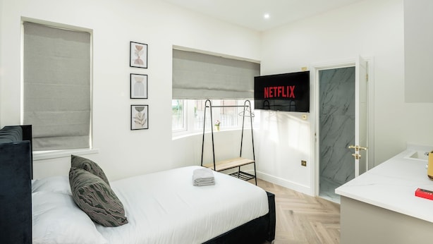 Quarto moderno com cama, televisão e banheiro.