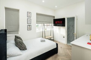 A modern bedroom with a bed, a TV, and a bathroom. - New London Studio 1 (London)