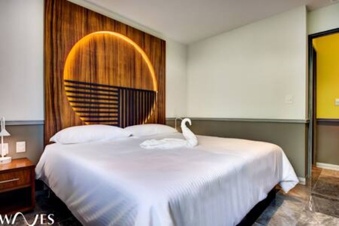 A hotel room with a bed, a wooden accent wall, a swan decoration, and a nightstand.