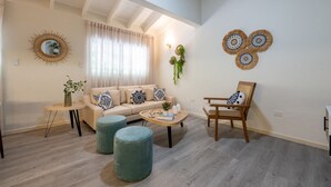 A living room with a sofa, two ottomans, a coffee table, a chair, and decorative wall art.