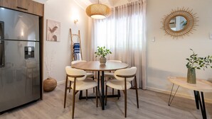 A modern kitchen with a built-in refrigerator, a dining table with four chairs, and a hanging light fixture.