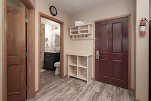 A hallway with a wooden door, a white shelf with hooks, and a red door. - NEW! Premium Unit 2216 - 1 Br - Zephyr Mountain Lodge (Winter Park)