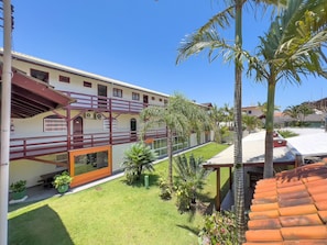 A multi-story building with a balcony, a well-maintained lawn, and several palm trees.