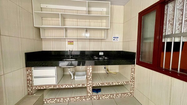 Una cocina con encimera negra, armarios blancos y salpicadero de azulejos.