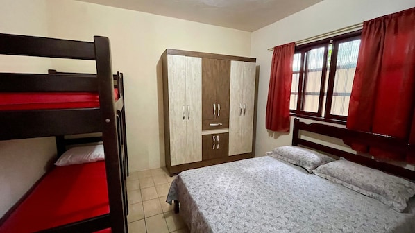 A room with bunk beds, a wardrobe, and a bed with a patterned bedspread.