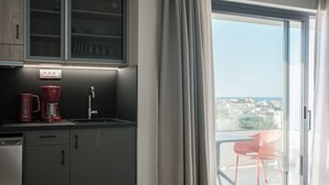 Une cuisine moderne équipée d’un lave-vaisselle intégré, d’une machine à café et d’un évier. Un balcon avec une chaise et une vue sur la ville est également à disposition.