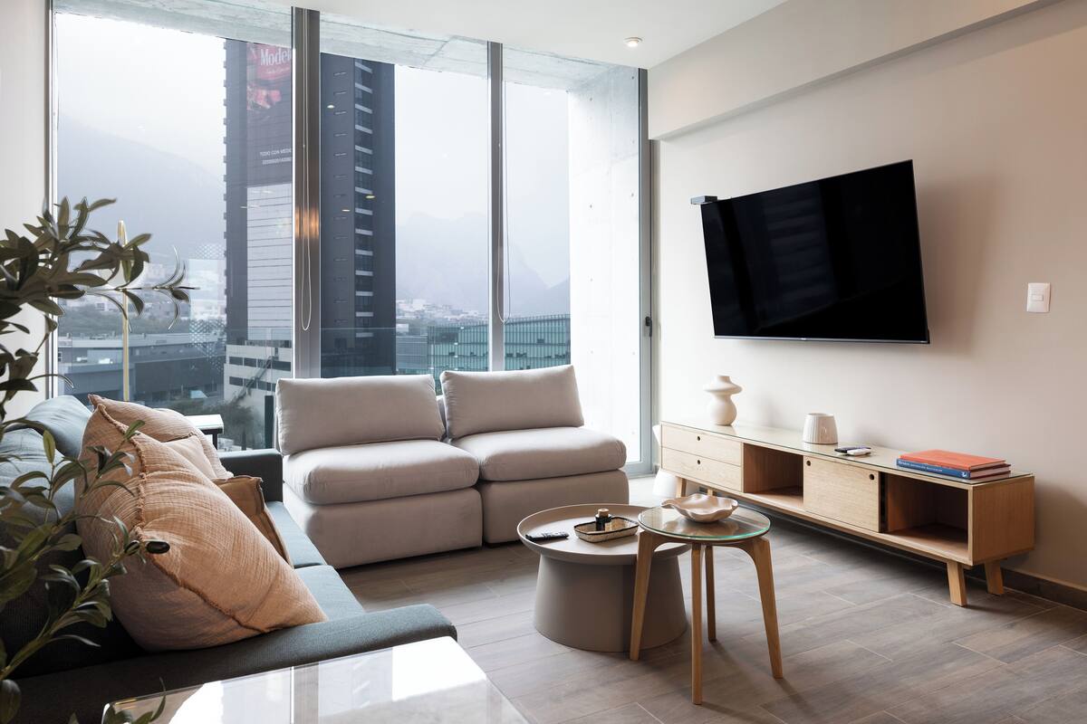 Una sala de estar moderna con un sofá, una mesa de centro y un televisor montado en la pared.