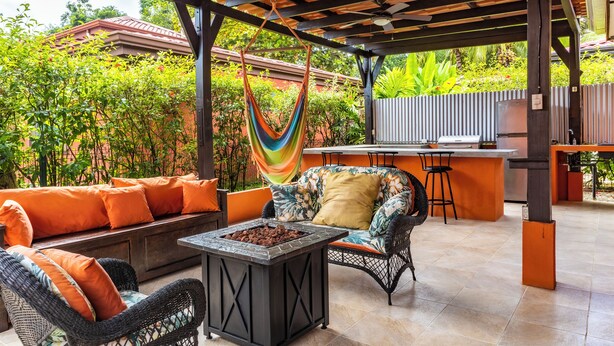 Une terrasse extérieure avec un canapé, des chaises, une table et un hamac.