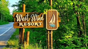 A wooden sign for West Wind Resort with a sailboat illustration.