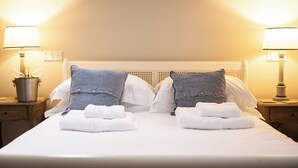 A hotel room with a neatly made bed, two bedside lamps, and a small table with a lamp and a potted plant. - St Tudy Inn (Bodmin)