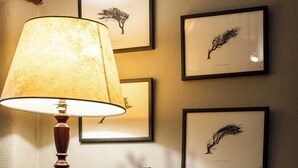 A room with a lamp, framed artwork on the wall, a cushion, and a small table with a candle. - St Tudy Inn (Bodmin)