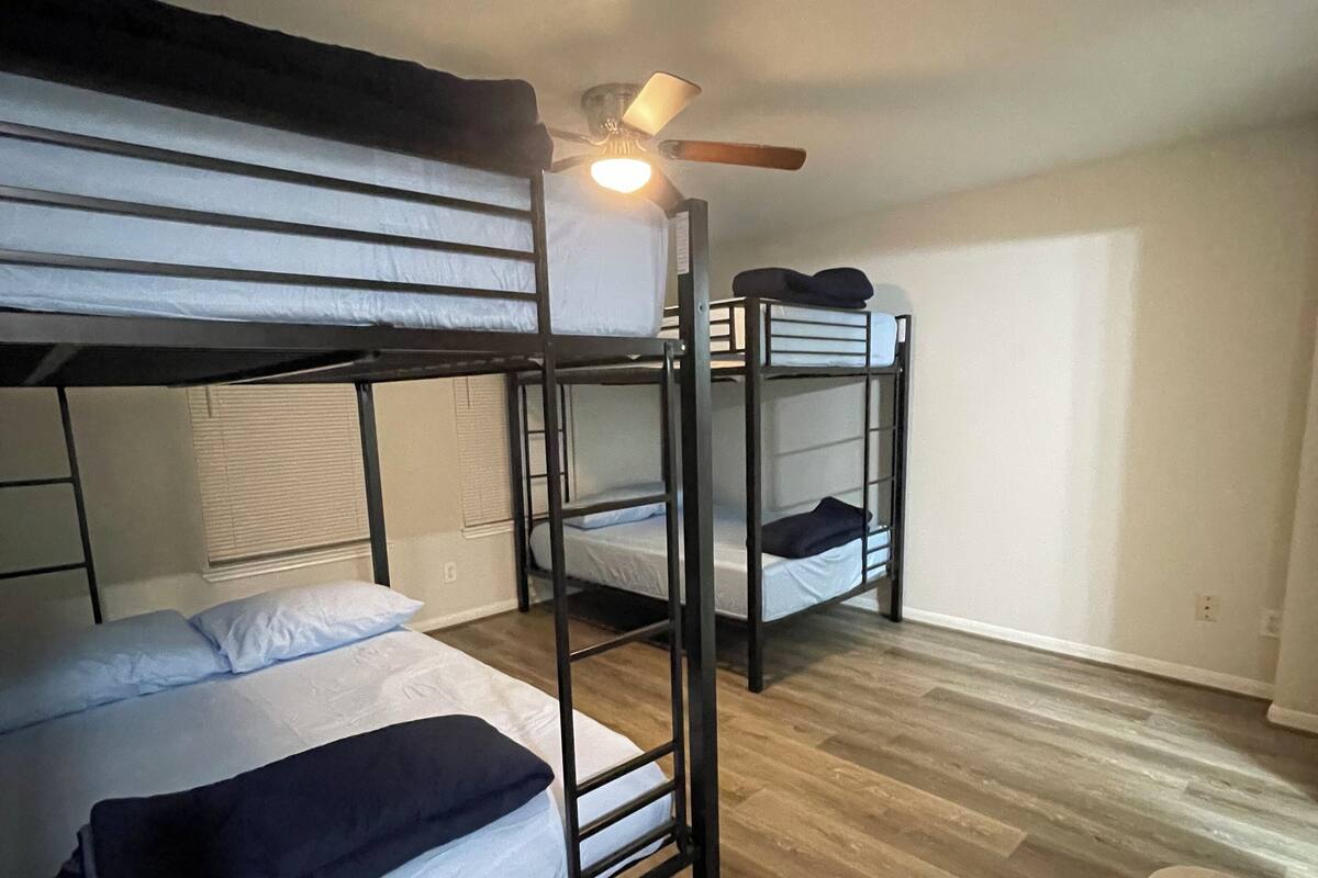 Ein Schlafsaalzimmer mit Etagenbetten, einem Deckenventilator und Holzboden.