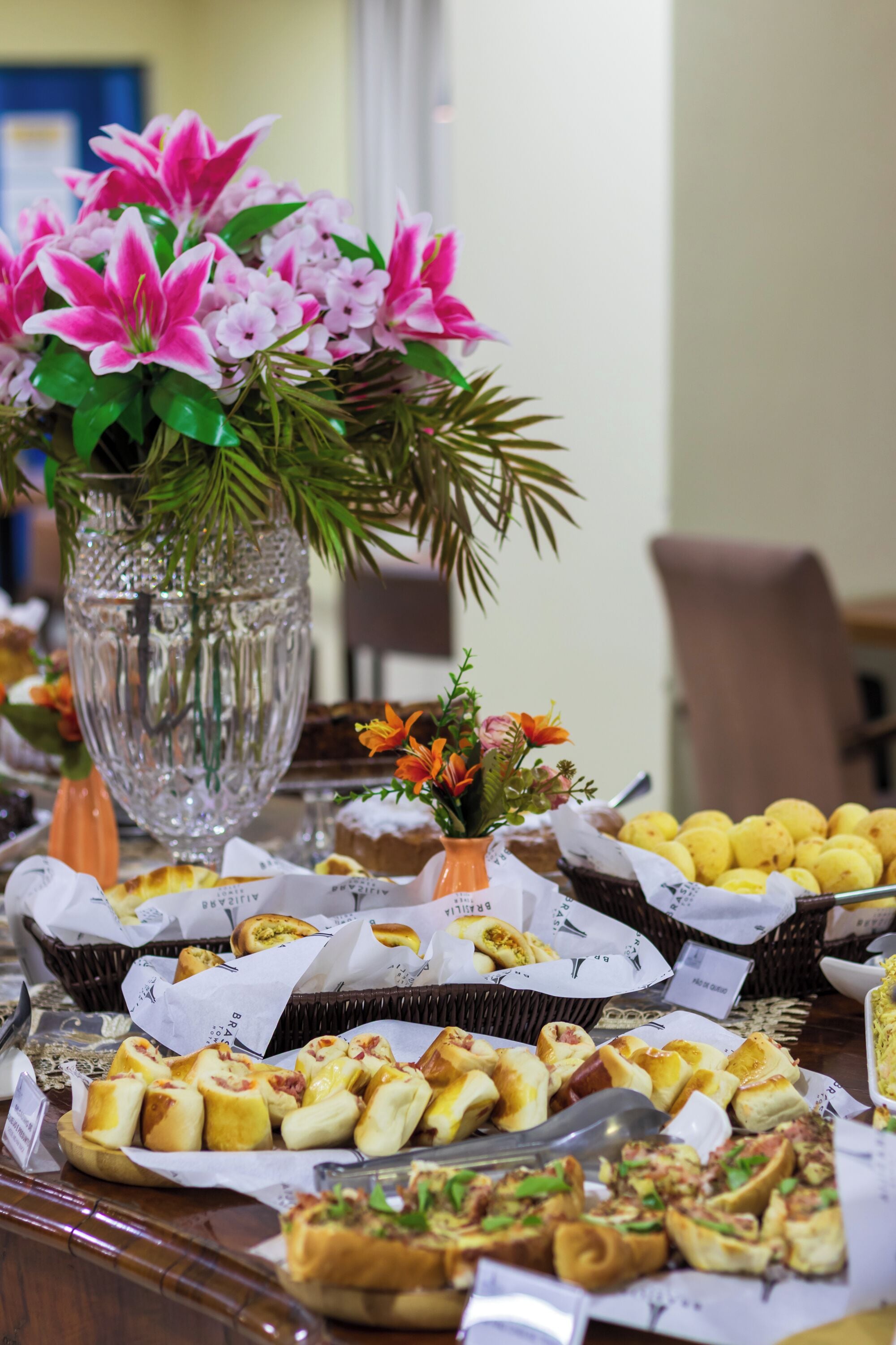 Una mesa de buffet con diversos alimentos y un jarrón de flores.