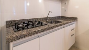 A kitchen with a granite countertop, stainless steel sink, and white cabinets. - Brasilia Tower Hotel by Castelo Itaipava (Brasília)