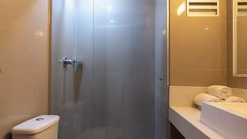 Un baño moderno con ducha envuelta en vidrio, inodoro y tocador con toallas.