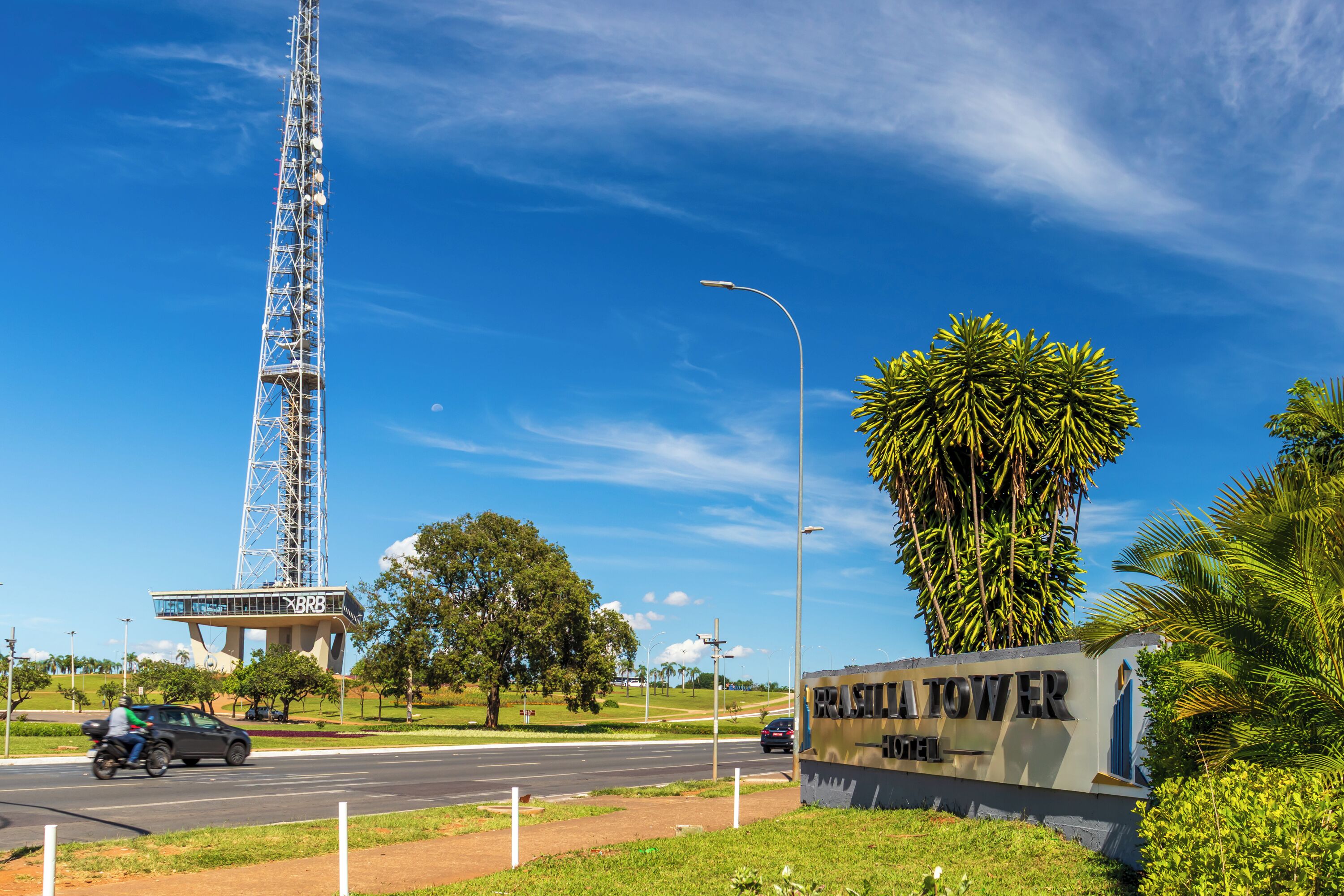 A sign for a tower hotel with a clear sky and palm trees in the foreground.