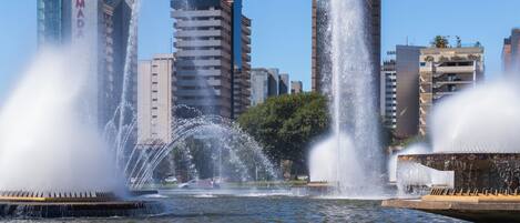 A cityscape with a central fountain surrounded by tall buildings, including a building with 'RAMADA' signage.