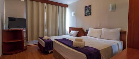 Habitación de hotel con dos camas, televisor, escritorio de madera y estantería.