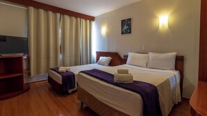 A hotel room with two beds, a TV, a wooden floor, and a painting on the wall. - Brasilia Tower Hotel by Castelo Itaipava (Brasília)