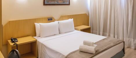 Una habitación de hotel con cama, mesitas de noche, escritorio y una silla.