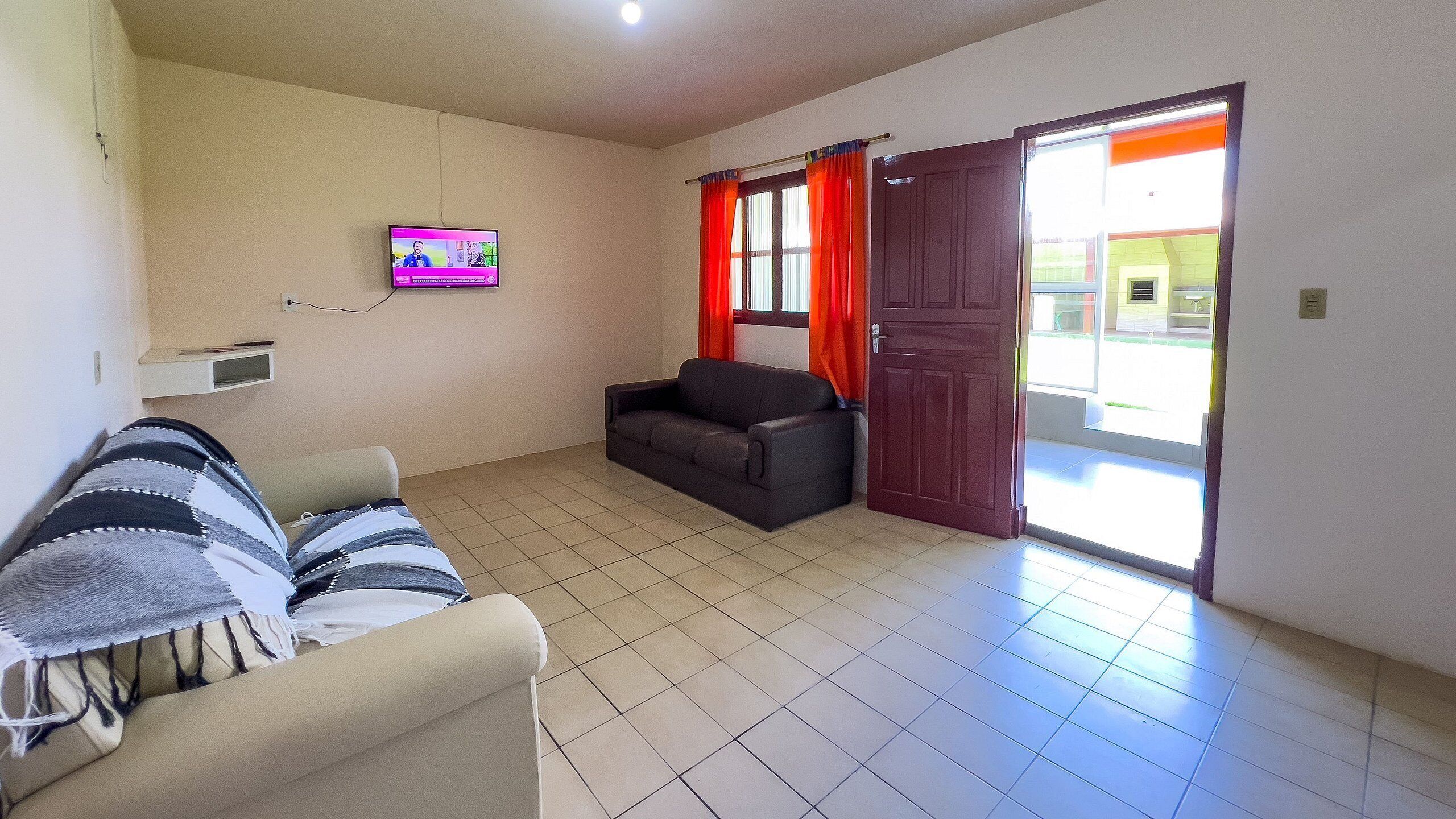 A living room with a sofa, a television, and a sliding glass door to the outside.