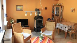 Una sala de estar acogedora con muebles de mimbre, una chimenea y una zona de comedor con una mesa.