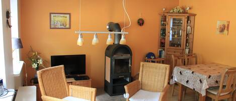 A cozy living room with wicker furniture, a fireplace, and a dining area with a table.