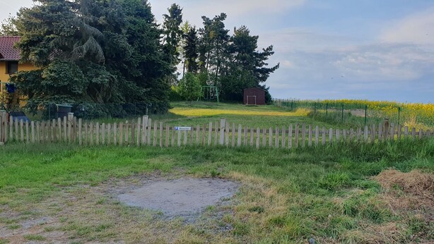 Un paisaje rural con una valla de madera, un columpio y un campo de flores amarillas.