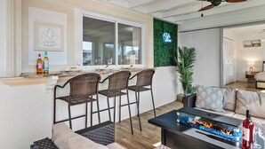A modern kitchen with a bar area, wicker chairs, and a fire feature. - Labor Day Sale: Gulf Access, Hot Tub, Kayaks, Fishing & Pet Friendly (North Fort Myers)