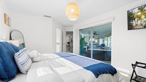 A bedroom with a bed, a hanging light fixture, a window, and a door leading to a balcony. - Labor Day Sale: Gulf Access, Hot Tub, Kayaks, Fishing & Pet Friendly (North Fort Myers)